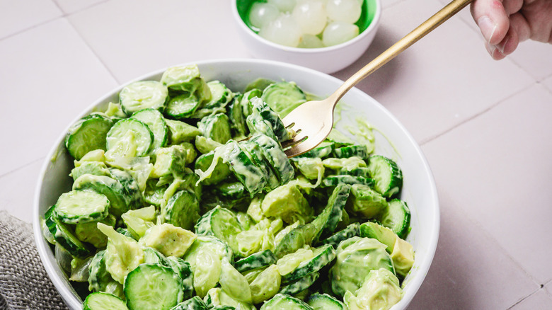 Lifting a forkful of avocado cucumber salad from bowl