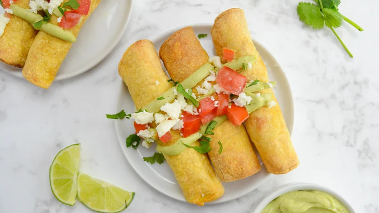 Air Fryer Chicken Taquitos and Avocado Crema on white plate with lime slices