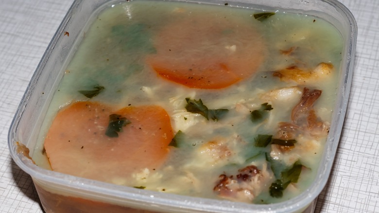 Homemade meat aspic with carrots and herbs in a container