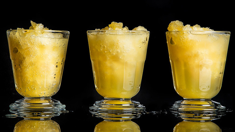 Three yellow frozen cocktails on black background