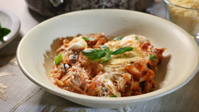 shallow bowl of baked gnocchi lasagna garnished with fresh basil leaves