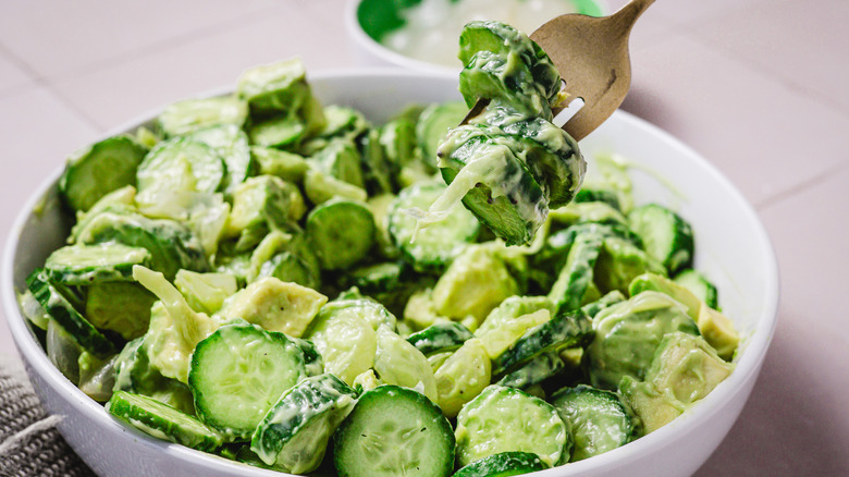 Lifting a forkful of avocado cucumber salad from bowl