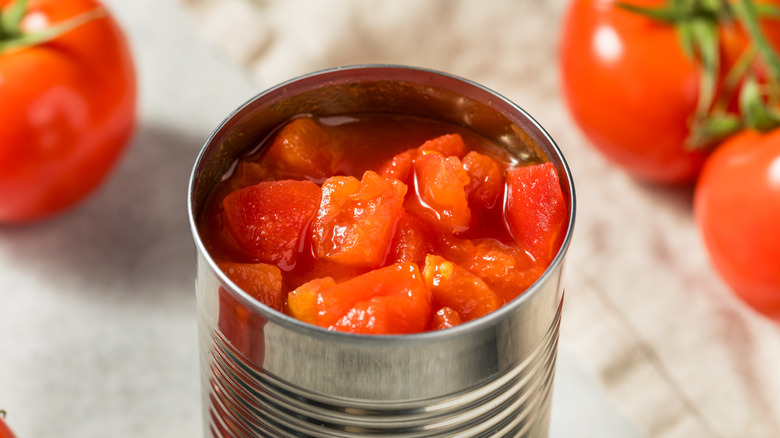 an open can of diced tomatoes with fresh tomatoes in the background