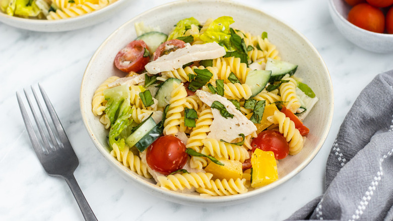 Bowl of chicken pasta salad with cucumber and cherry tomatoes