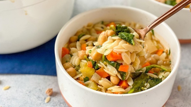 Spooning chickpea orzo soup from bowl