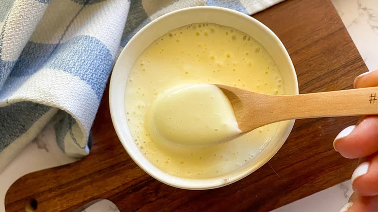 A person stirring copycat Kewpie Mayo with a wooden spoon