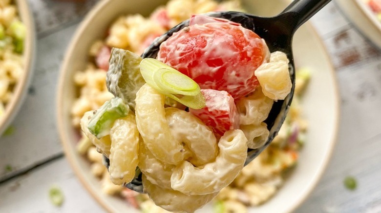 Spooning macaroni salad from bowl