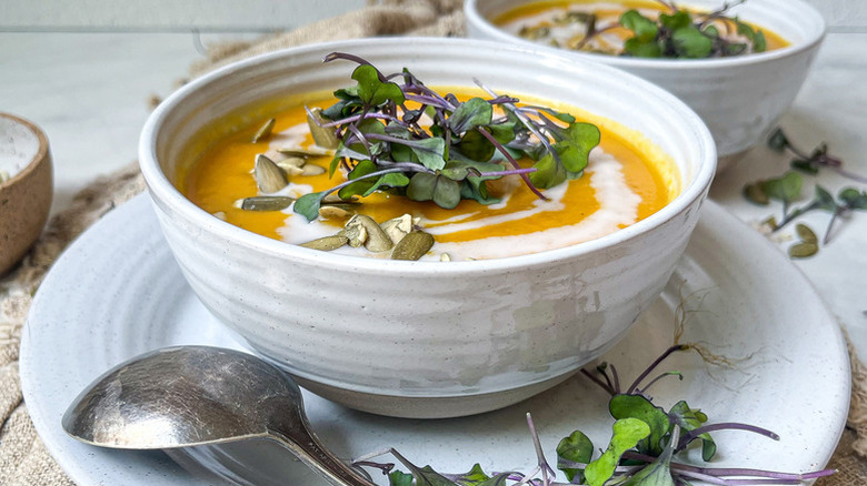 Bowl of roasted acorn squash soup, garnished with microgreens