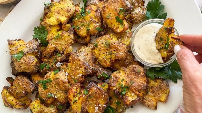 Crispy smashed potatoes on plate with creamy dip