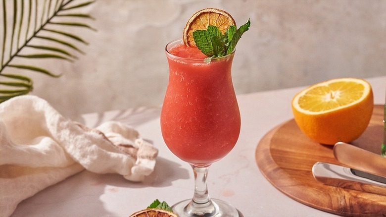 Frozen strawberry daiquiri cocktail garnished with mint sprigs and dried orange round