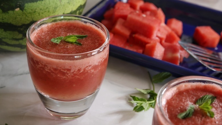 Frozen watermelon cocktail in a glass next to a tray of watermelon chunks