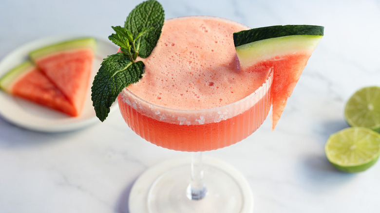Frothy watermelon cocktail garnished with fresh mint and a watermelon wedge