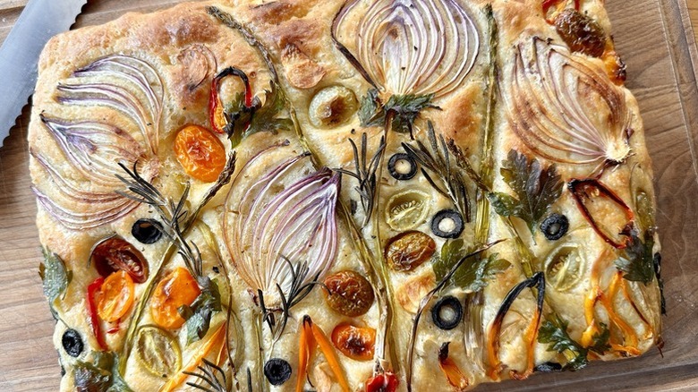 Garden art vegetable-topped focaccia loaf on a wooden board
