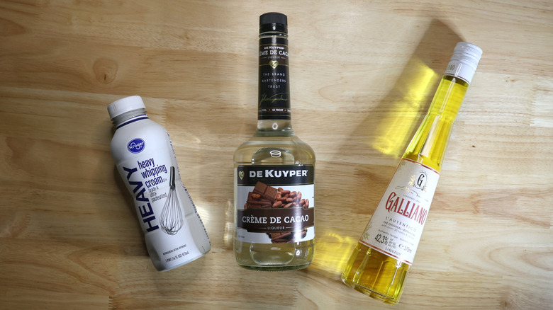 bottles of heavy cream, Galliano liqueur, and white crème de cacao on wooden table