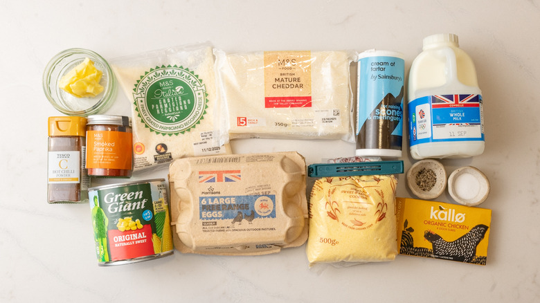 carton of eggs, can of corn, jug of whole milk, and other cheesy corn souffle ingredients laid out