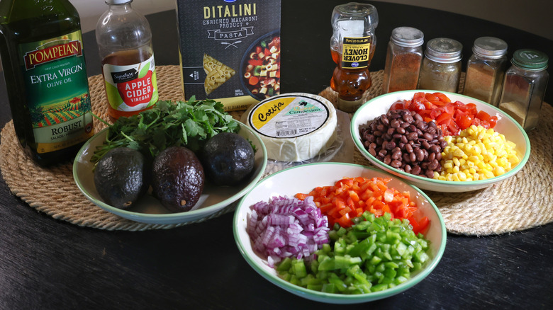 cowboy caviar pasta salad ingredients laid out on a black table