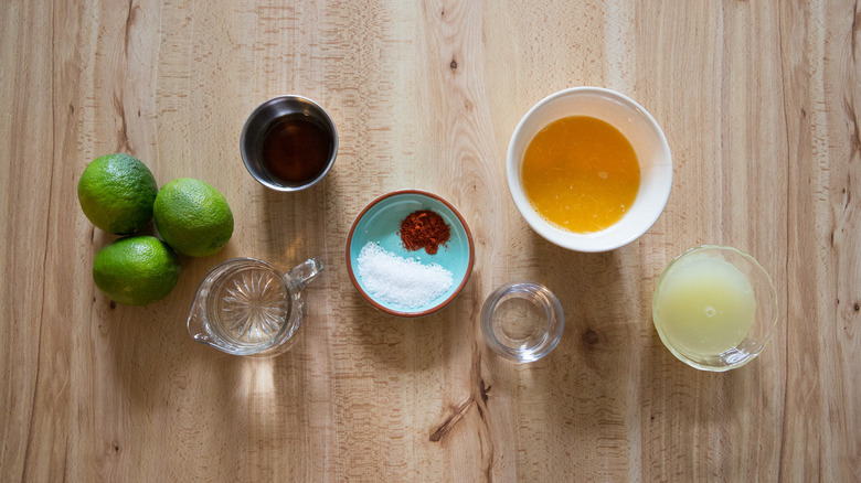 limes, bowl of orange juice, and other margarita popsicle ingredients on table