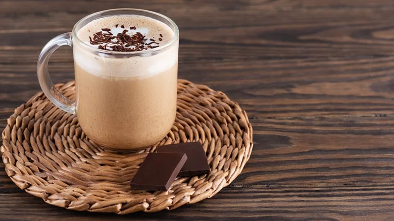 Image of hot chocolate next to chocolate squares on wood table