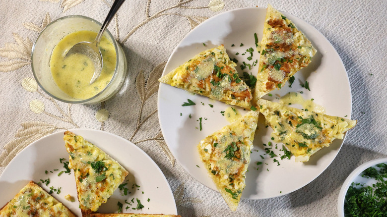 an overhead view of four egg toasts artfully arranged on a small plate with minced parsley and vinaigrette beside them