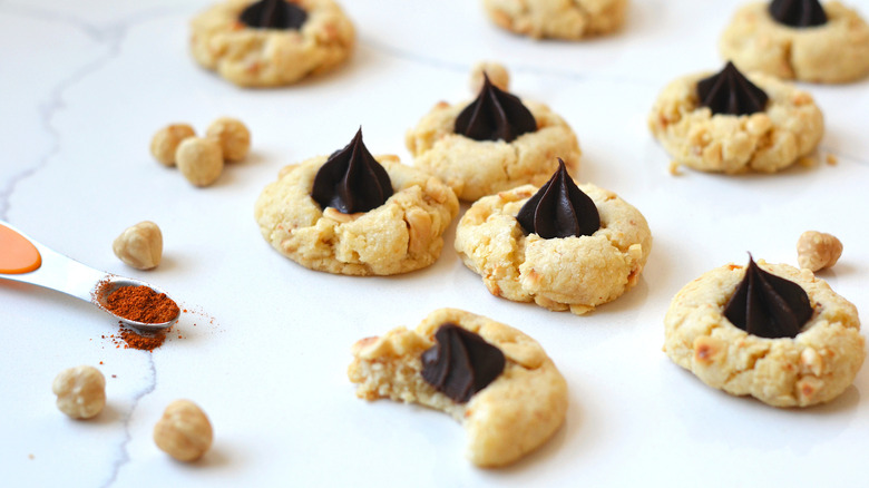 Hazelnut thumbprint cookies filled with chocolate ganache on a white countertop 
