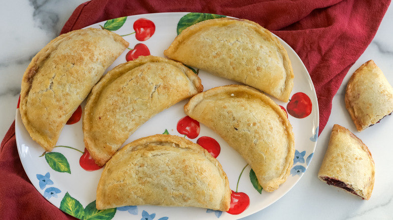 sweet, gooey cherry pie empanadas on a plate