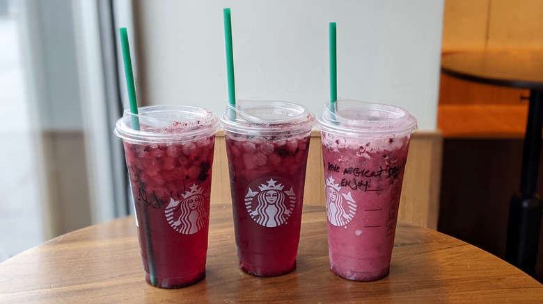Starbucks Blackberry and Sage Refreshers are lined up on a table.