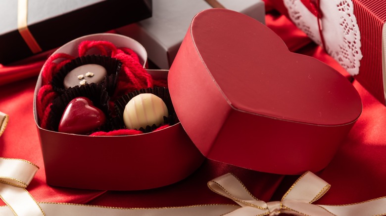 A small, red, heart-shaped box with three chocolates