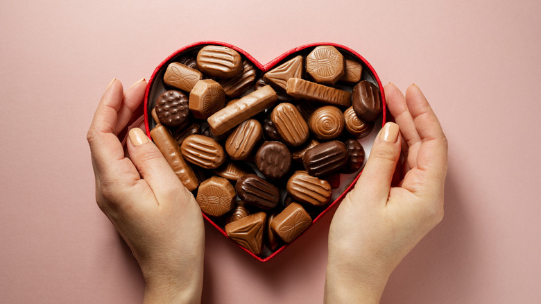 Hands holding a heart-shaped Valentine's Day chocolate box