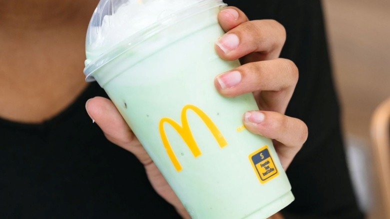 Close-up of a hand holding a McDonald's Shamrock Shake