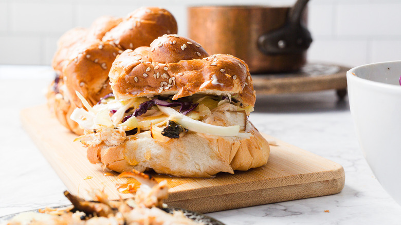 Chicken sliders on cutting board with sauce in background and salad in the foreground