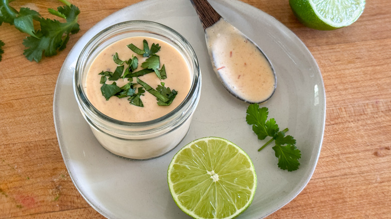 small jar of chipotle crema next to lime
