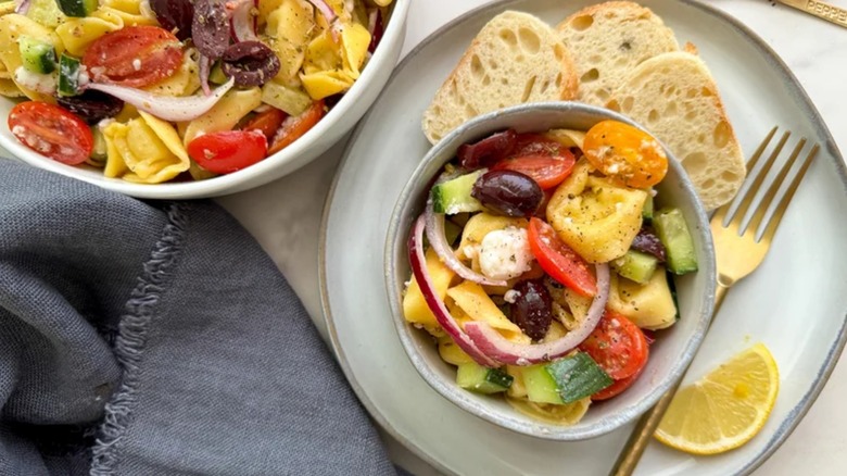 Tortellini Greek Salad in two bowls with sliced baguette
