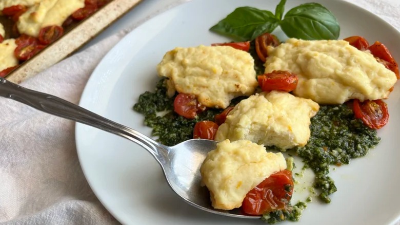Sheet pan gnudi with pesto and tomatoes on white plate