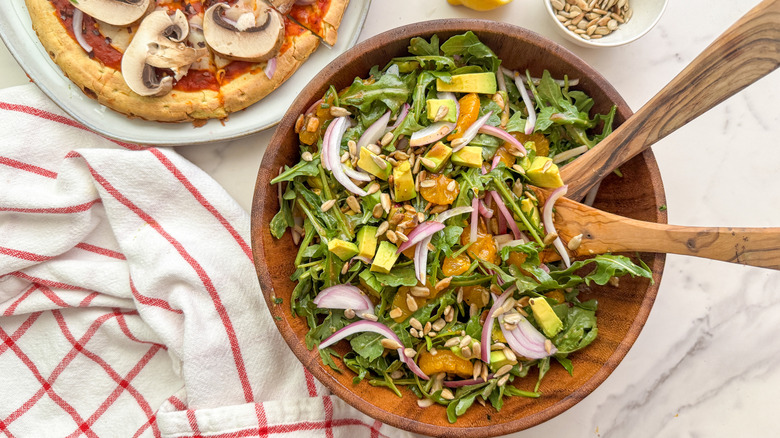 salad in wood bowl with pizza