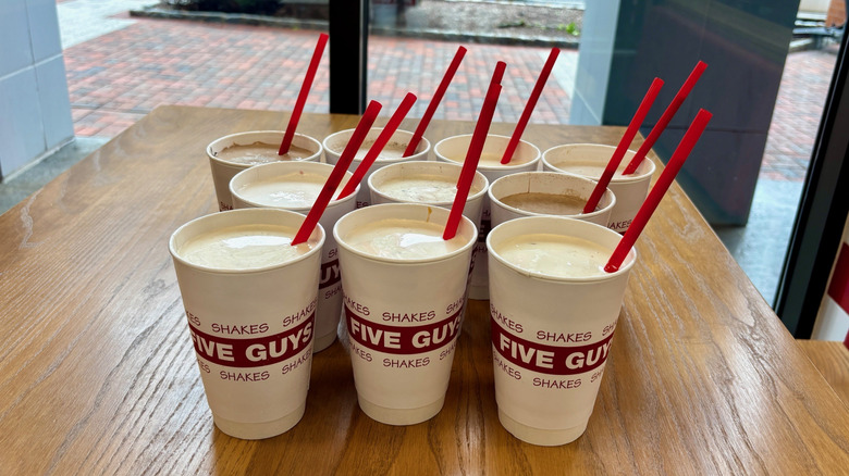 10 different Five Guys milkshakes on a table at a Five Guys restaurant