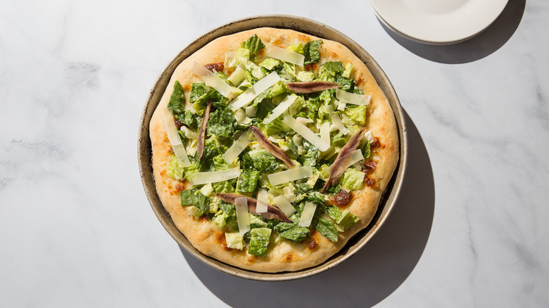 Caesar salad pizza on table