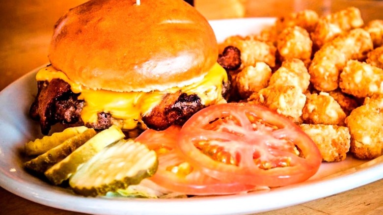 Burger served with tater tots and lettuce, pickles and tomatoes