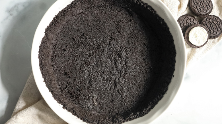 Oreo pie crust in dish with chocolate cookie sandwiches on the side