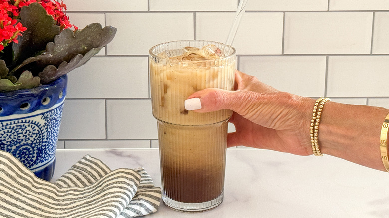 hand holding glass espresso drink