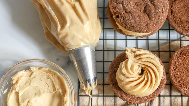 espresso frosting in piping tube and spread on cookie