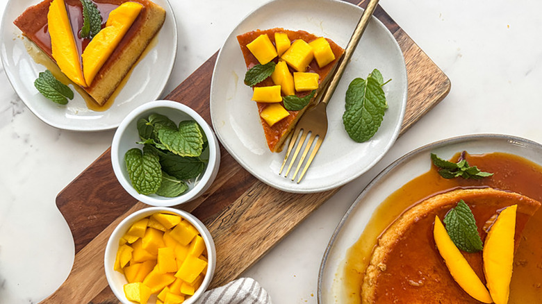 Portions of mango flan on plates with fresh mango and mint