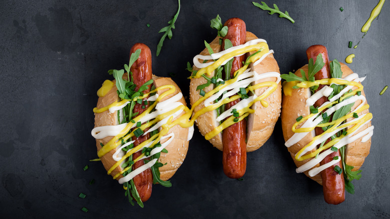 Three hot dogs drizzled with mustard and mayo