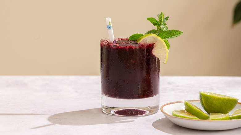 frozen blueberry mojito next to a plate of lime wedges and lime half
