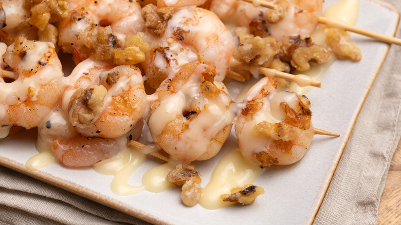 close up of skewers of grilled honey walnut shrimp on a dish