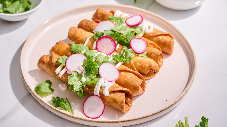 beef flautas on a plate with cilantro and radishes