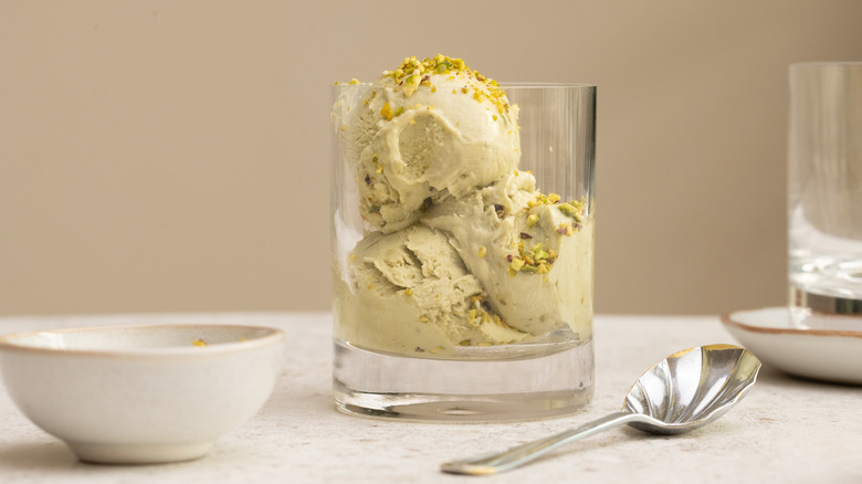 Three scoops of 3-ingredient pistachio ice cream in a glass cup next to spoon