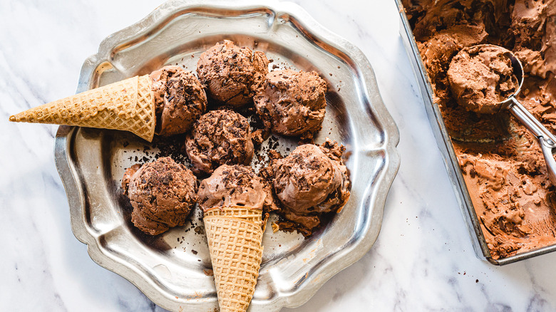 Plate with chocolate ice cream cones bestide pan of ice cream