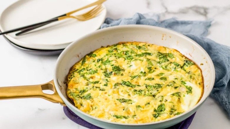skillet with spinach quiche next to plate