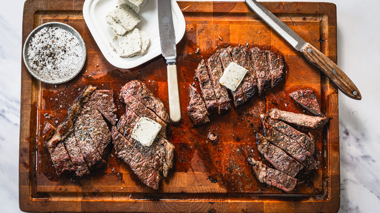 Picanha steaks with garlic butter on cutting board with knives