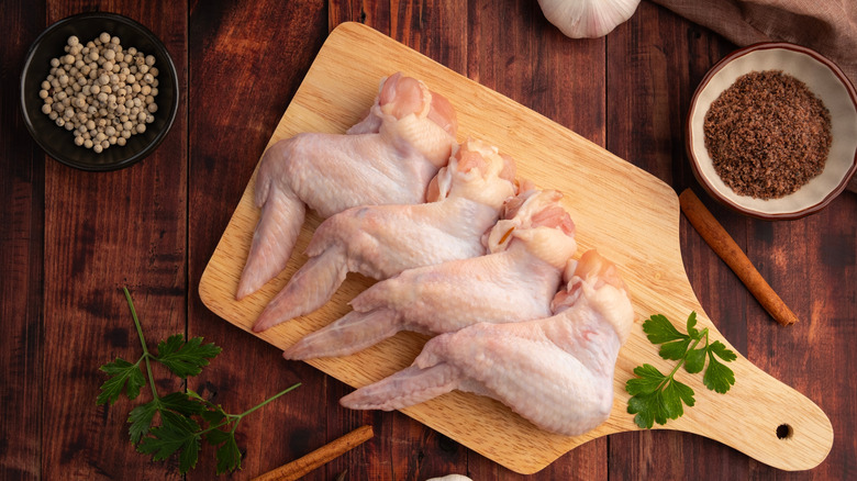 raw chicken wings on wood board with spices